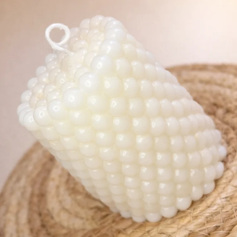 Vela artesanal cilíndrica con textura de pequeñas perlas