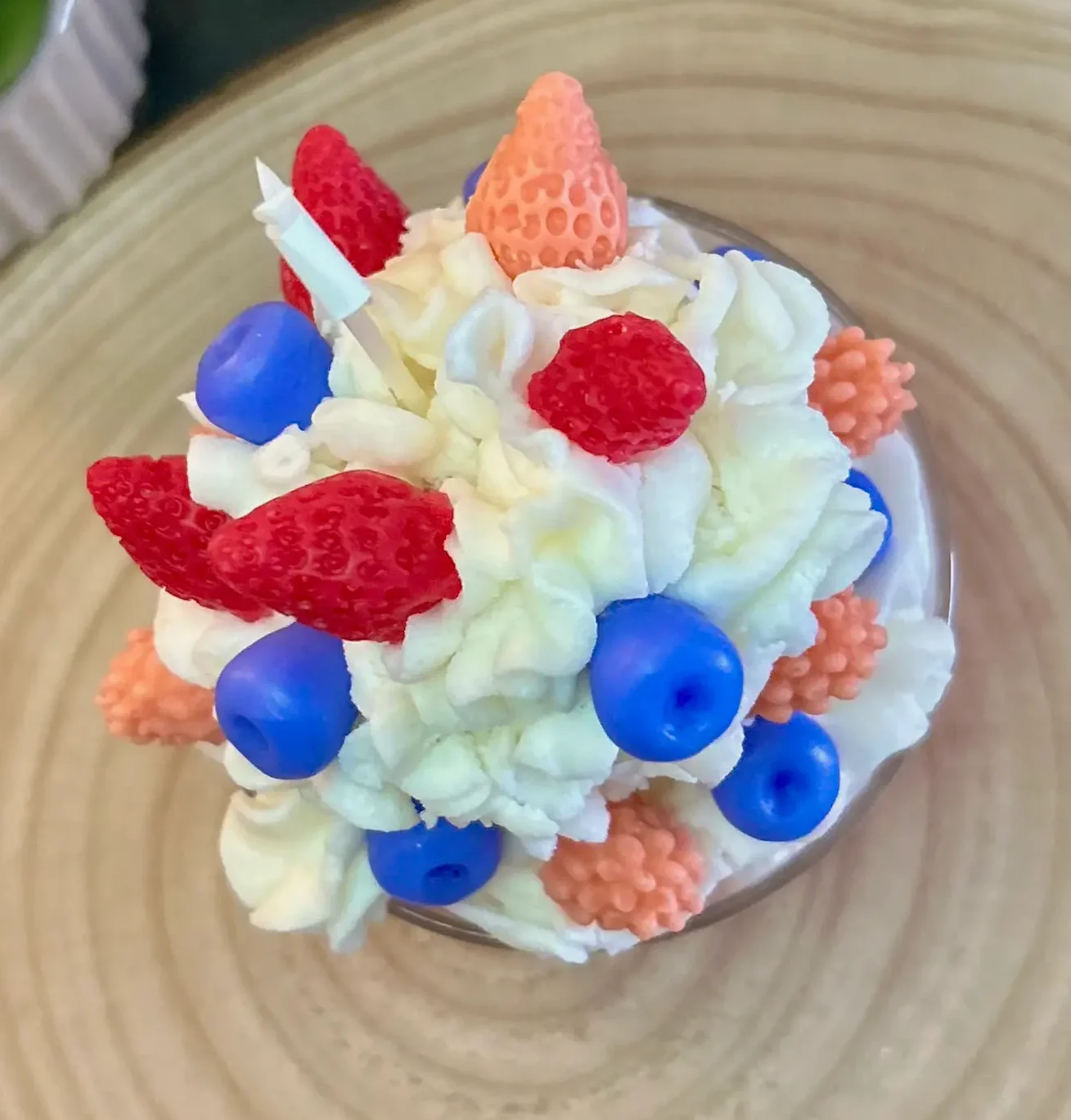 Delicia Berry es una vela artesanal inspirada en la estética de un postre delicado. Su efecto chantilly en relieve, coronado con pequeños frutos rojos decorativos, crea una pieza visualmente irresistible. La textura cremosa de la parte superior aporta volumen y realismo, mientras que los detalles frutales añaden contraste y un toque divertido y moderno. Es una vela que combina dulzura, creatividad y sofisticación, perfecta para quienes buscan algo diferente y llamativo.