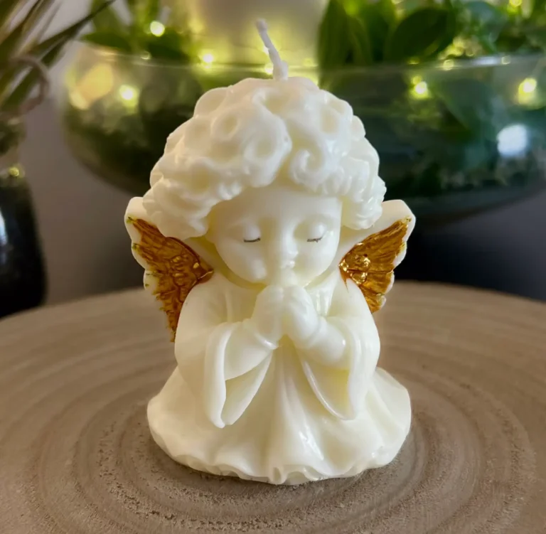 Luz de Ángel es una vela artesanal de un pequeño ángel con las manos unidas en oración, ojos cerrados y expresión tranquila, evocando calma y recogimiento.